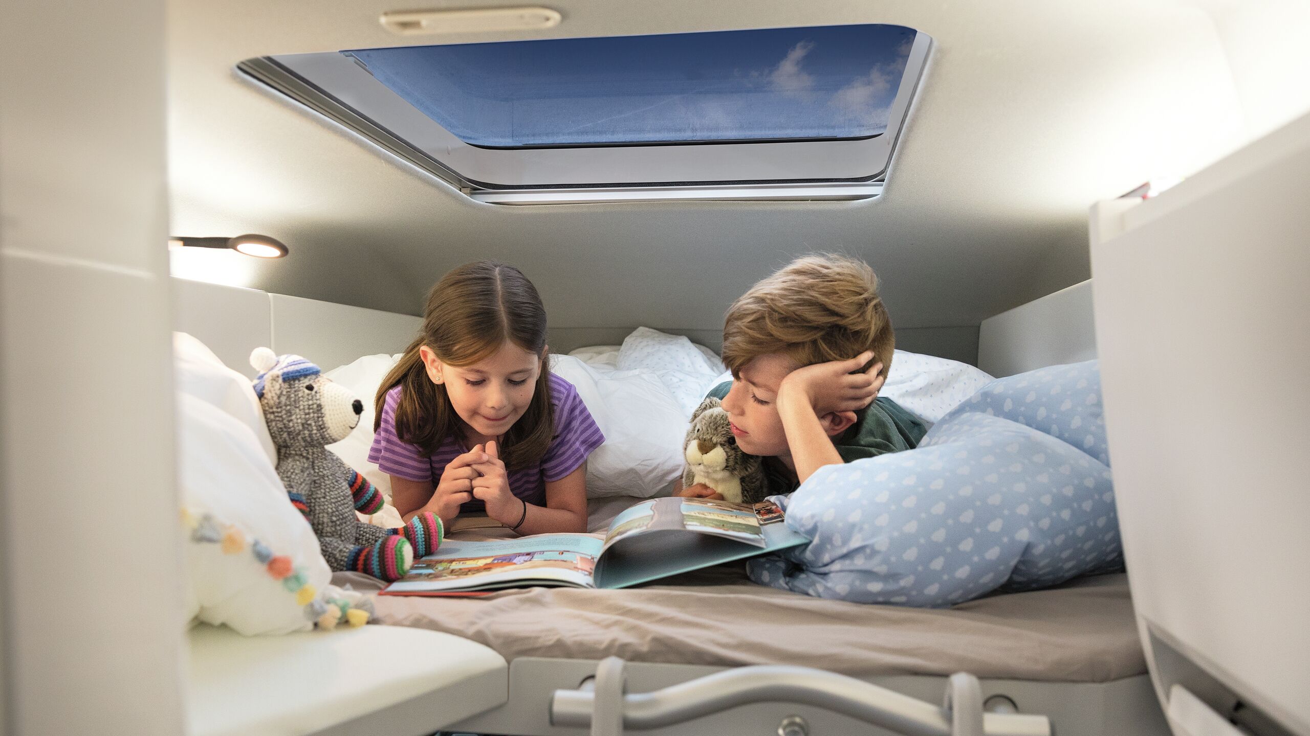 Duas crianças deitam-se na cama de trás na VW Grand California.