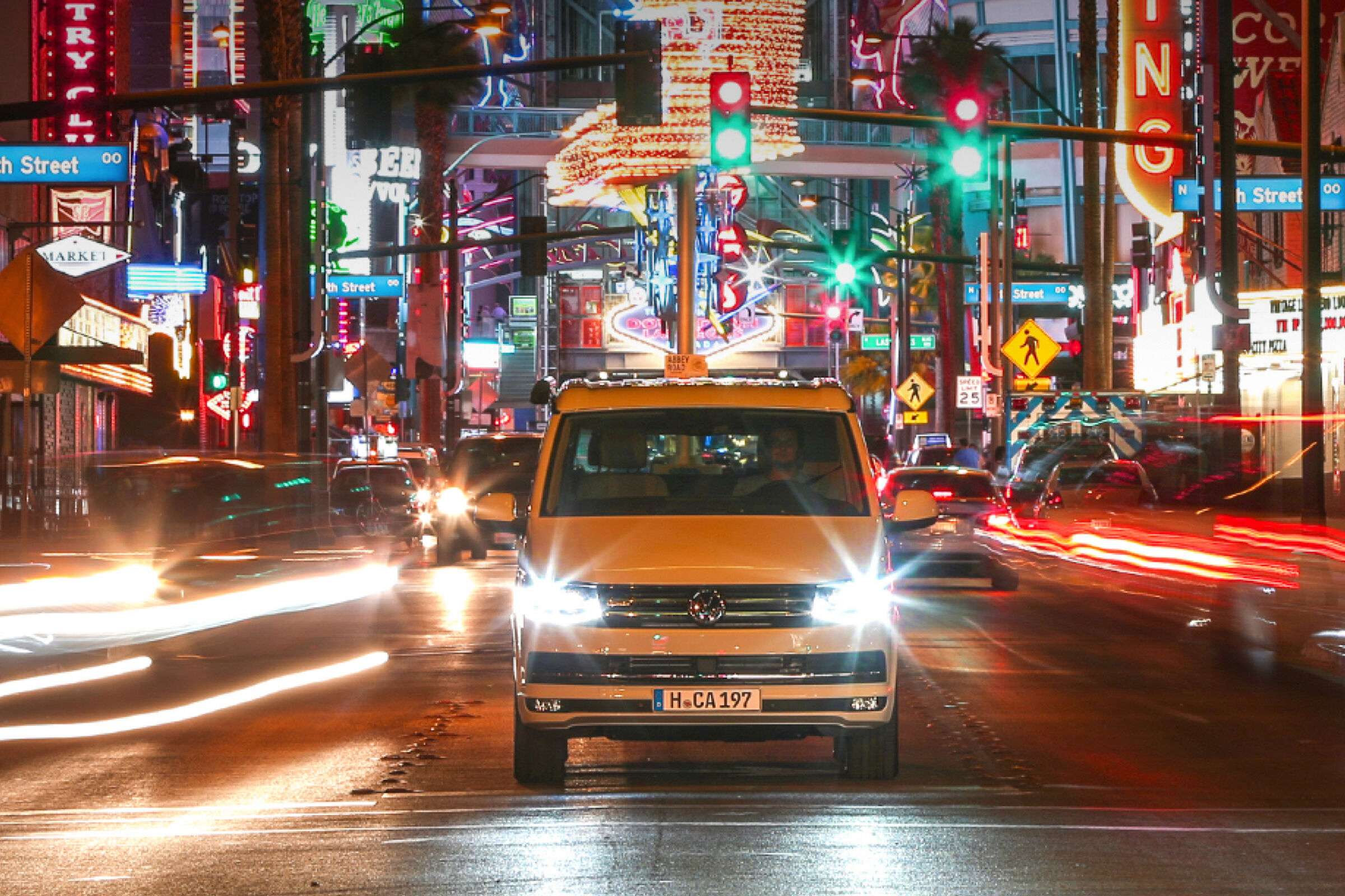 A California da Volkswagen Veículos Comerciais num dos centros urbanos californianos. Em seu redor estão vários letreiros luminosos coloridos.