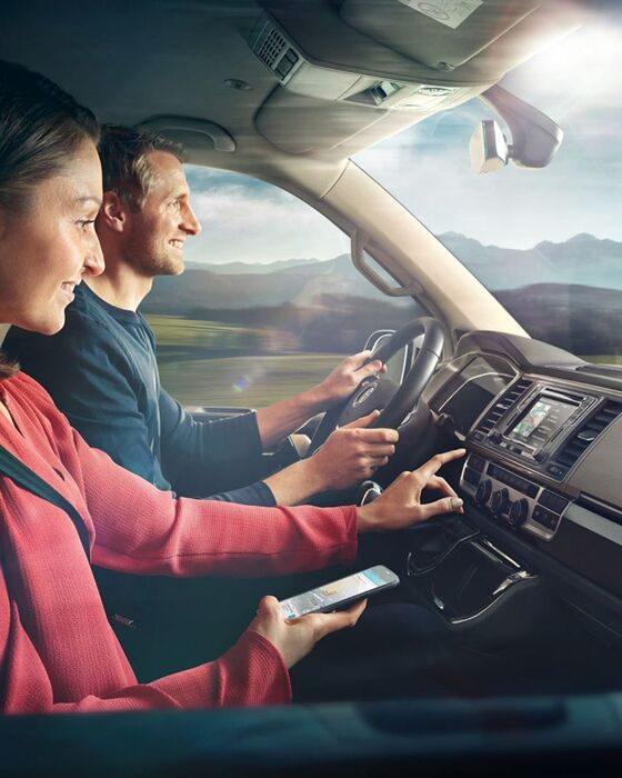 Um homem e uma mulher no cockpit de uma carrinha comercial Volkswagen.