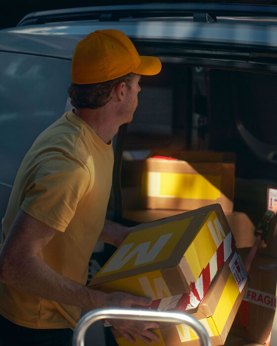 Um homem carrega a nova carrinha VW Caddy Cargo com caixotes.
