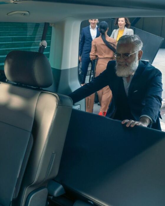 Um homem está a mudar a disposição dos bancos na carrinha VW Caravelle.