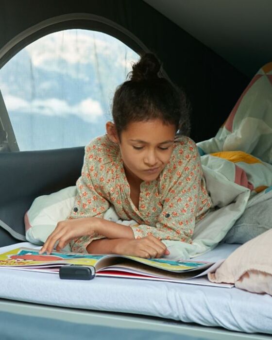Uma criança deitada na cama alta da Volkswagen California 6.1.