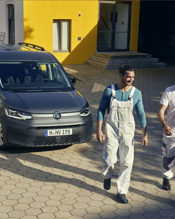Dois homem afastam-se do VW Caddy Kombi