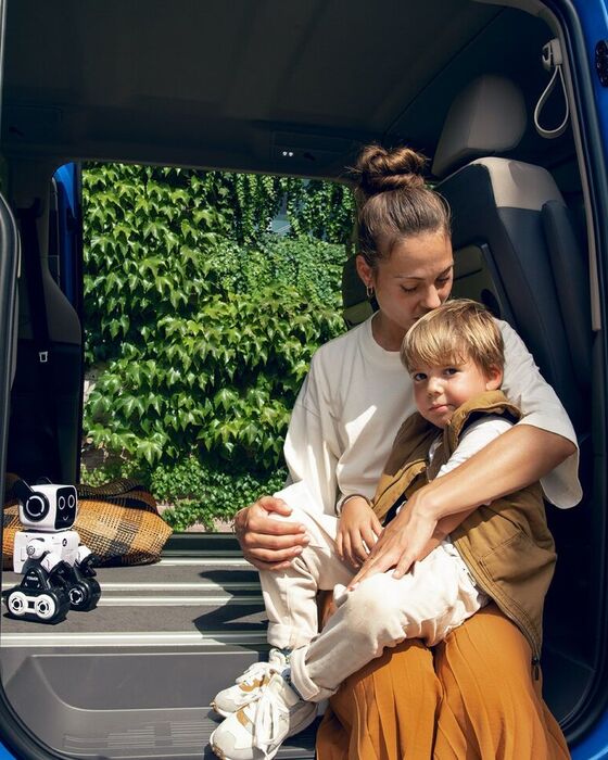 Eine Mutter sitzt mit ihrem Sohne im Rahmen der Schiebetür des VW Mutlivan T7 2021