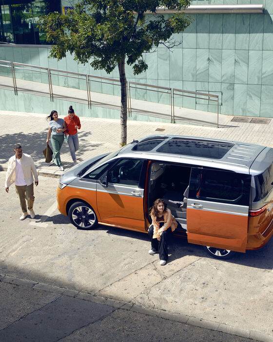 Jovens em volta de um VW Multivan Energetic estacionado.