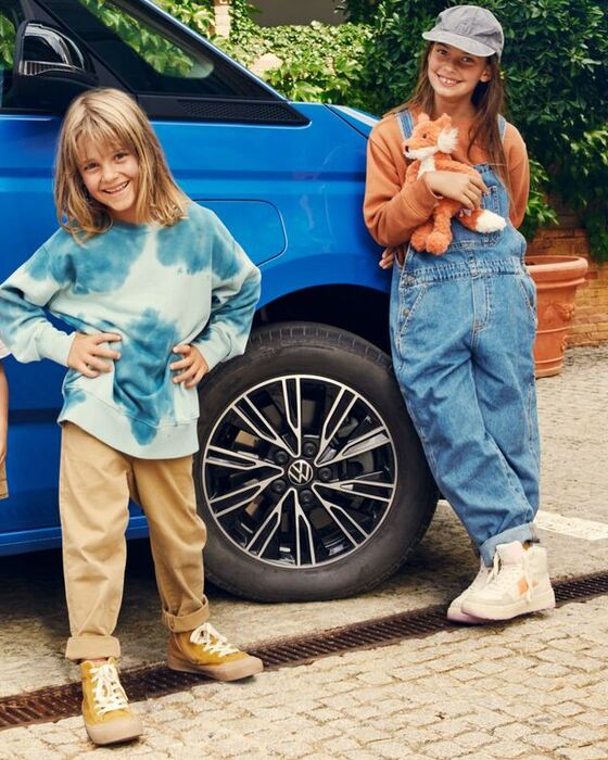 Três crianças ao lado da Multivan da Volkswagen.