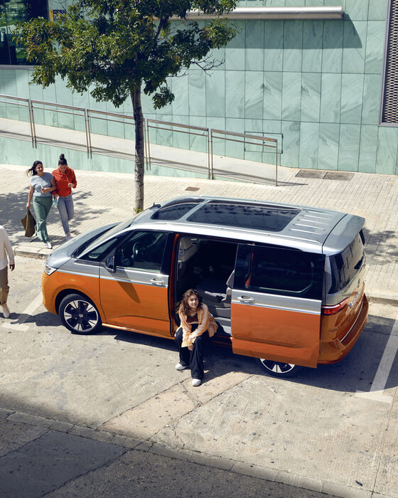 Mulher senta-se na porta traseira aberta da Multivan Energetic da Volkswagen.