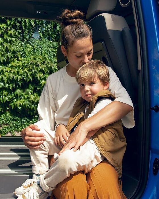 Uma mulher sentada com um rapaz na porta lateral do Multivan Energetic da Volkswagen.