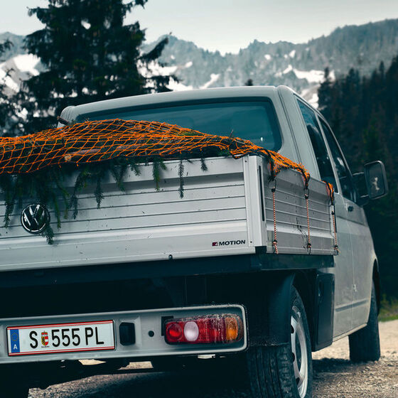 Um VW Transporter 6.1 de Caixa Aberta está a conduzir numa estrada montanhosa