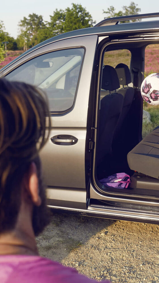 Criança lança a bola pelo interior do VW Caddy Maxi com as portas deslizantes abertas