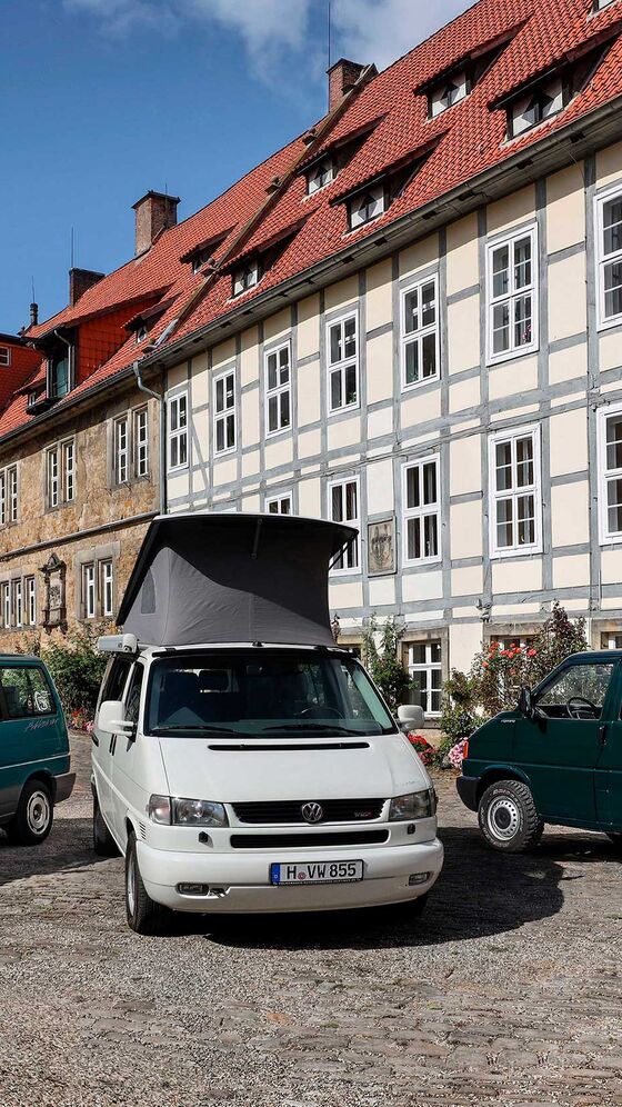 Três VW T4 em frente a uma casa típica na Alemanha.