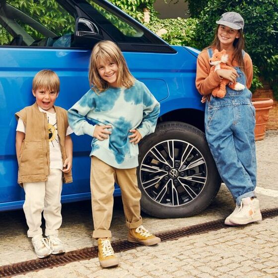 Três crianças em frente ao VW Multivan.