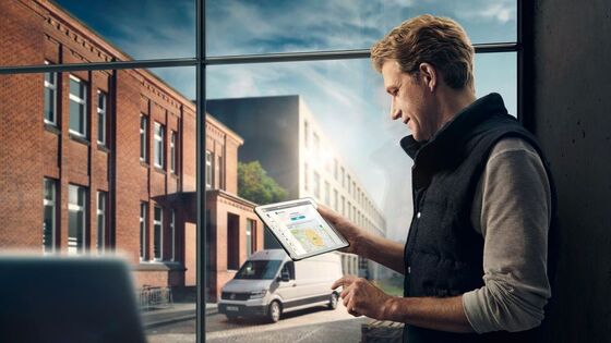 Um homem utiliza o Car-Net num tablet. Do lado de fora está estacionada uma carrinha Volkswagen.
