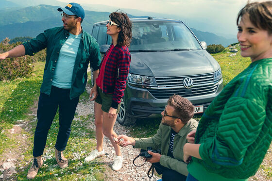 Quatro pessoas em frente a uma carrinha de passageiros Volkswagen Caravelle 6.1