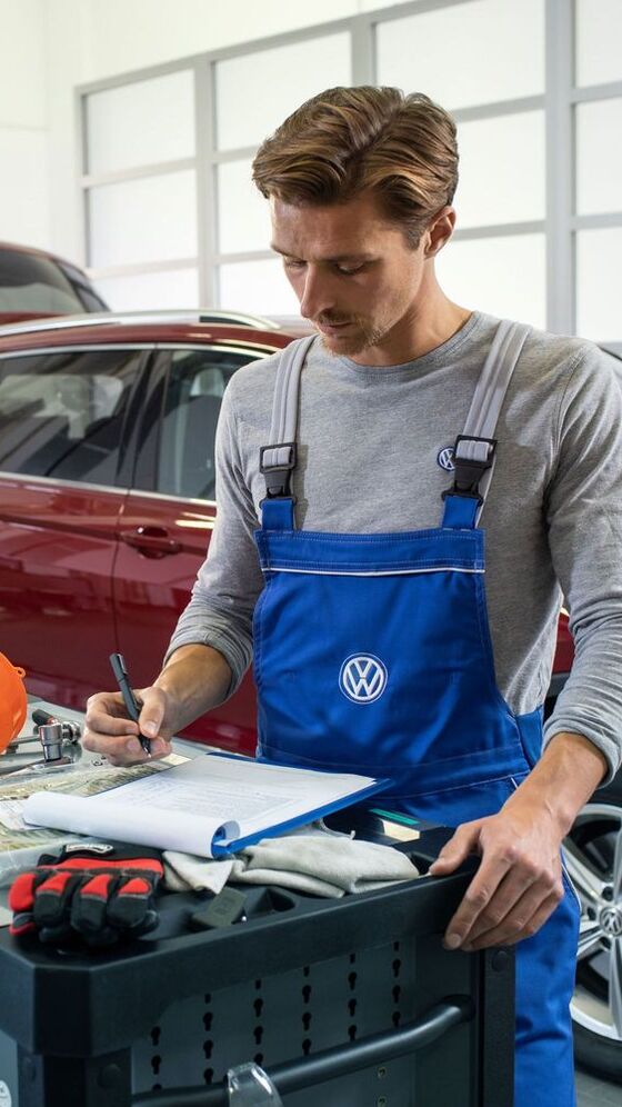 Empregado de serviço da VW verifica um carro com condução a gás natural numa oficina