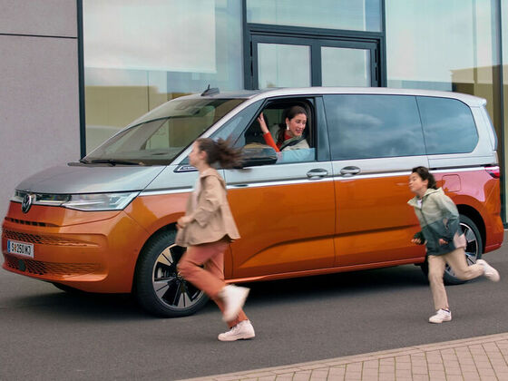Mulher sentada na nova VW Multivan e crianças a correr para o carro