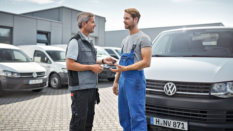 Um homem entrega as chaves da sua carrinha VW a um funcionário Volkswagen