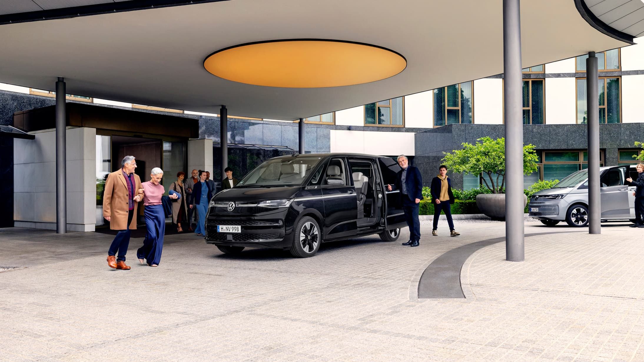 Várias pessoas à volta de uma Volkswagen Multivan 8 lugares