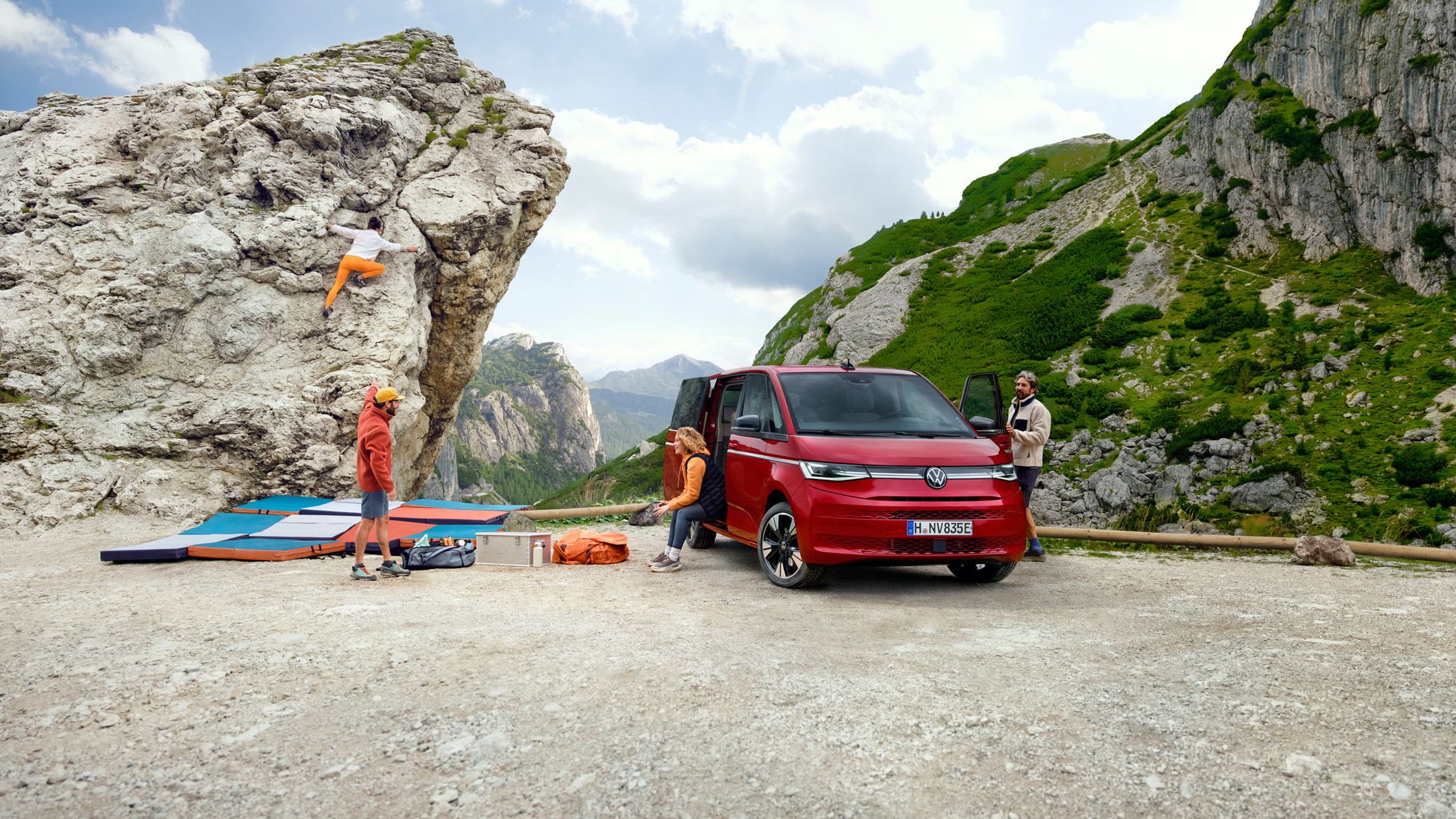 Volkswagen Multivan numa paisagem de montanhas com um grupo de pessoas a escalar.